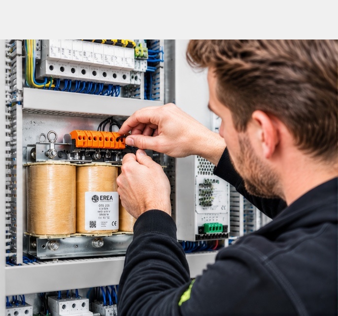 Installateur sluit een EREA-transformator aan in een schakelkast